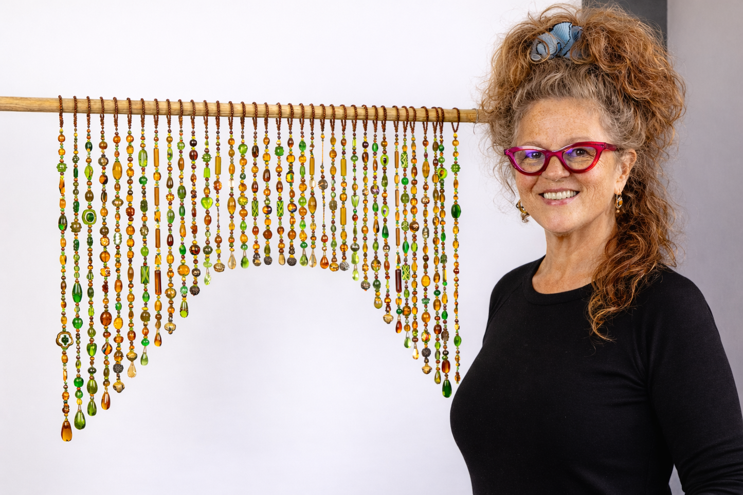 artist with handmade brown amber and green glass beaded curtain arch