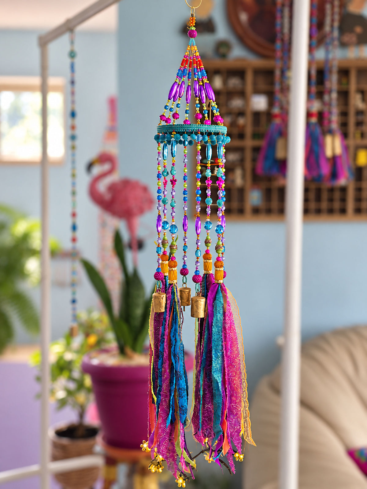Full-length handmade boho mobile with turquoise frame, colorful beaded strands and textile tassels in an eclectic room.