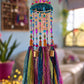 Colorful bohemian hanging mobile with glass beads, turquoise circular frame, brass bells and flowing fabric tassels.