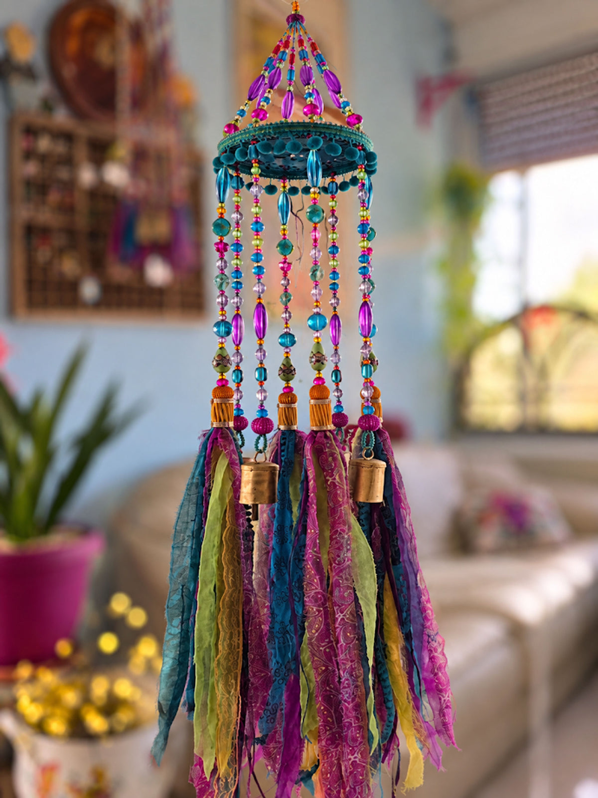 Colorful bohemian hanging mobile with glass beads, turquoise circular frame, brass bells and flowing fabric tassels.