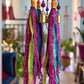 Close-up of pink, blue, purple and green fabric tassels with colorful beads and small brass bells.
