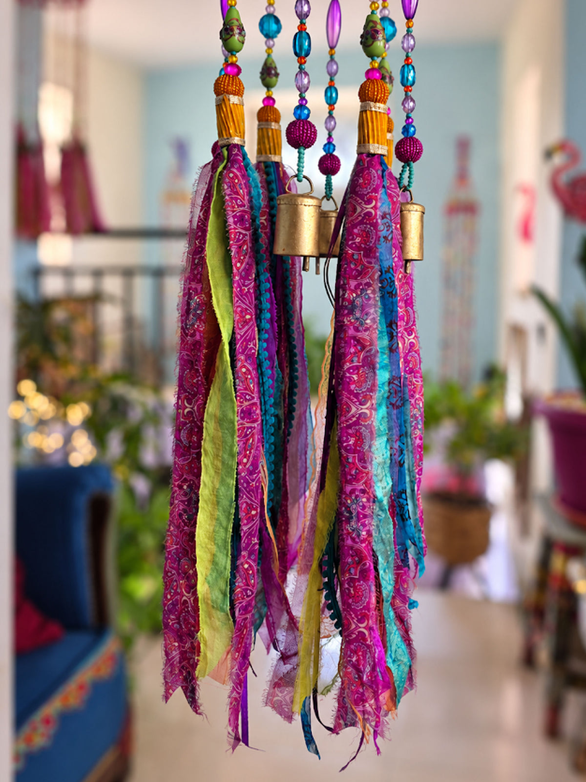 Close-up of pink, blue, purple and green fabric tassels with colorful beads and small brass bells.
