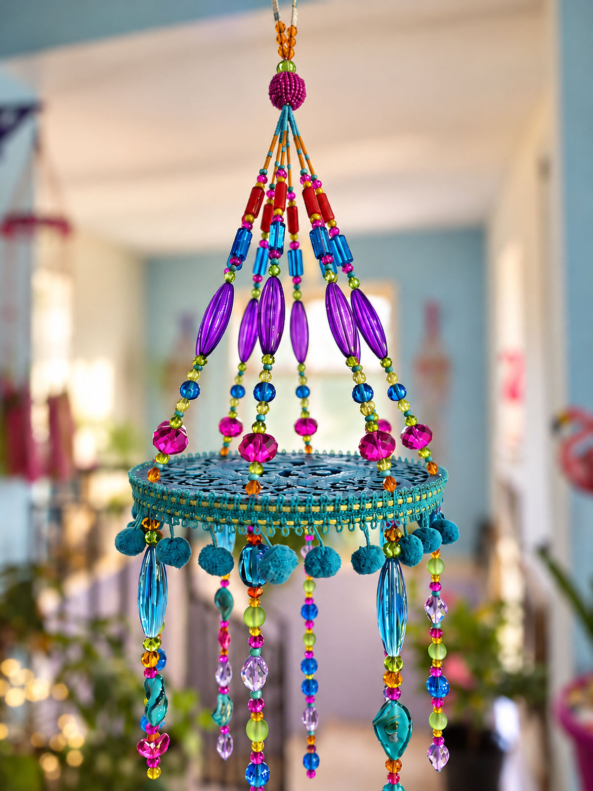 Detailed view of turquoise circular mobile frame with purple, pink and blue glass beads and decorative trim.