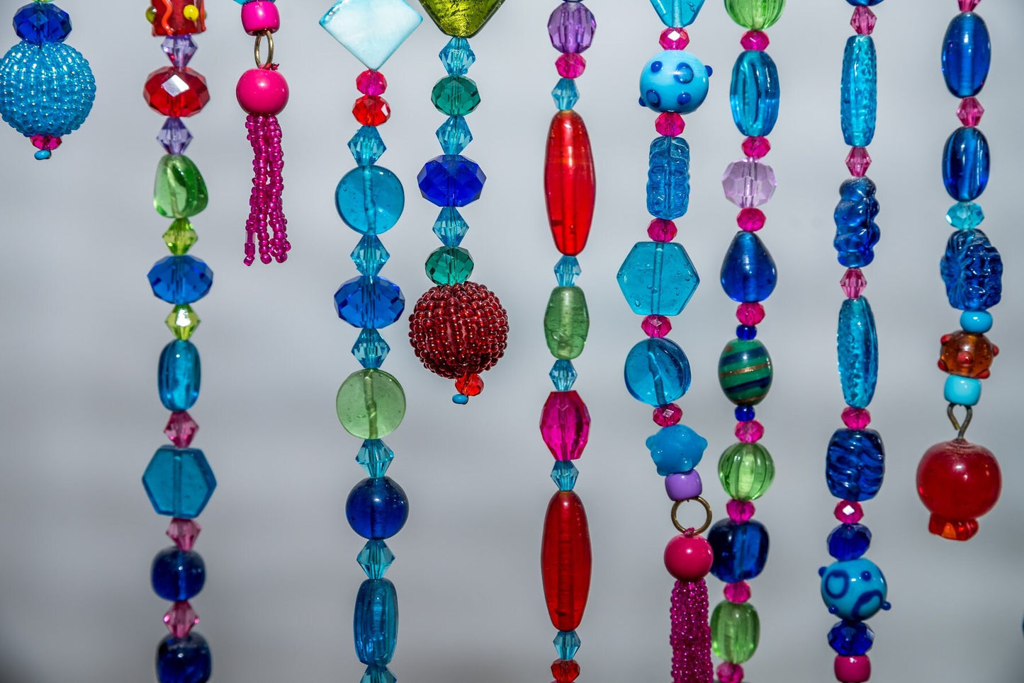 Unique Handmade Beaded curtain Arch Shape in Shadows of Blue, Turquoise, Green, Purple, Red, and Fuchsia.